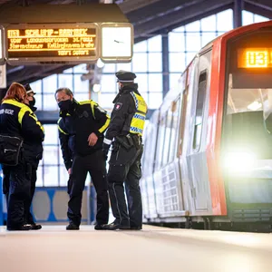 Polizisten stehen auf dem Bahnsteig im Bahnhof, daneben ein Zug der Linie U3