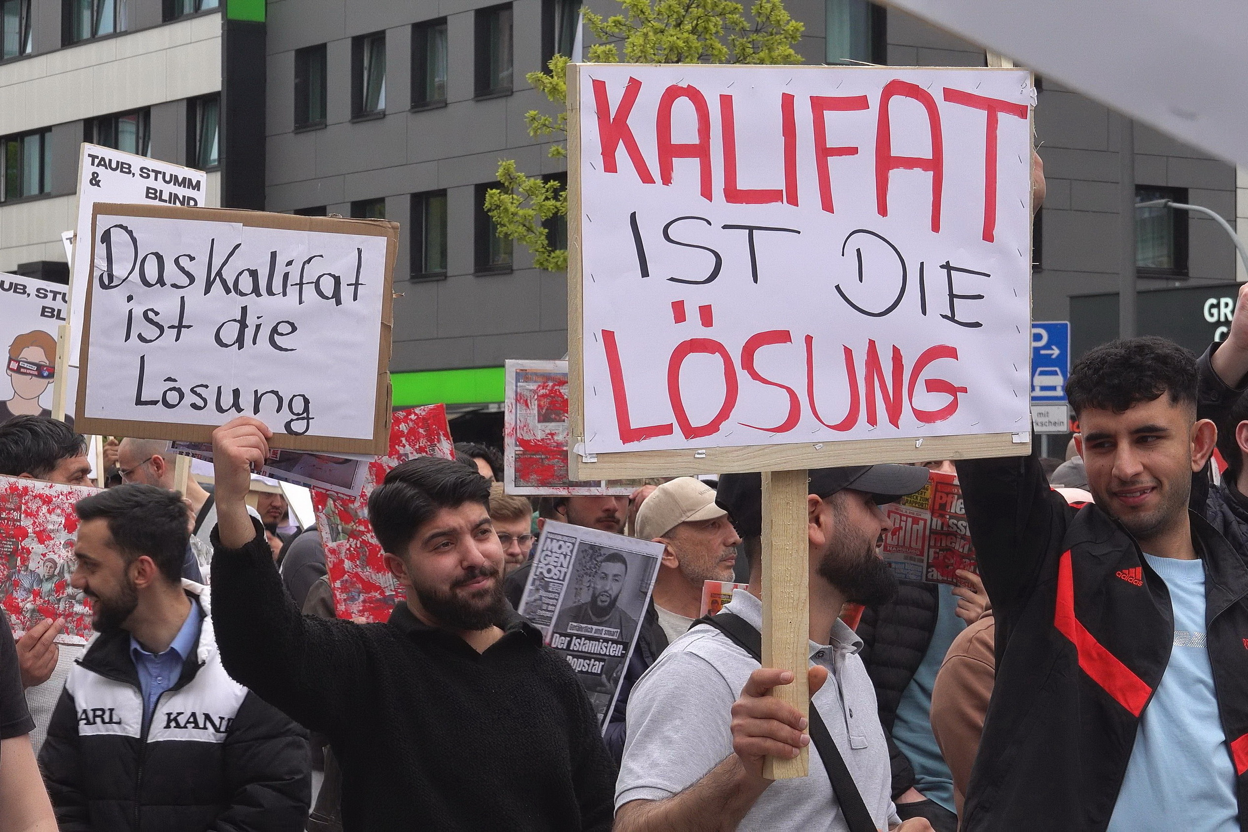 Männer halten Schilder hoch: „Das Kalifat ist die Lösung“