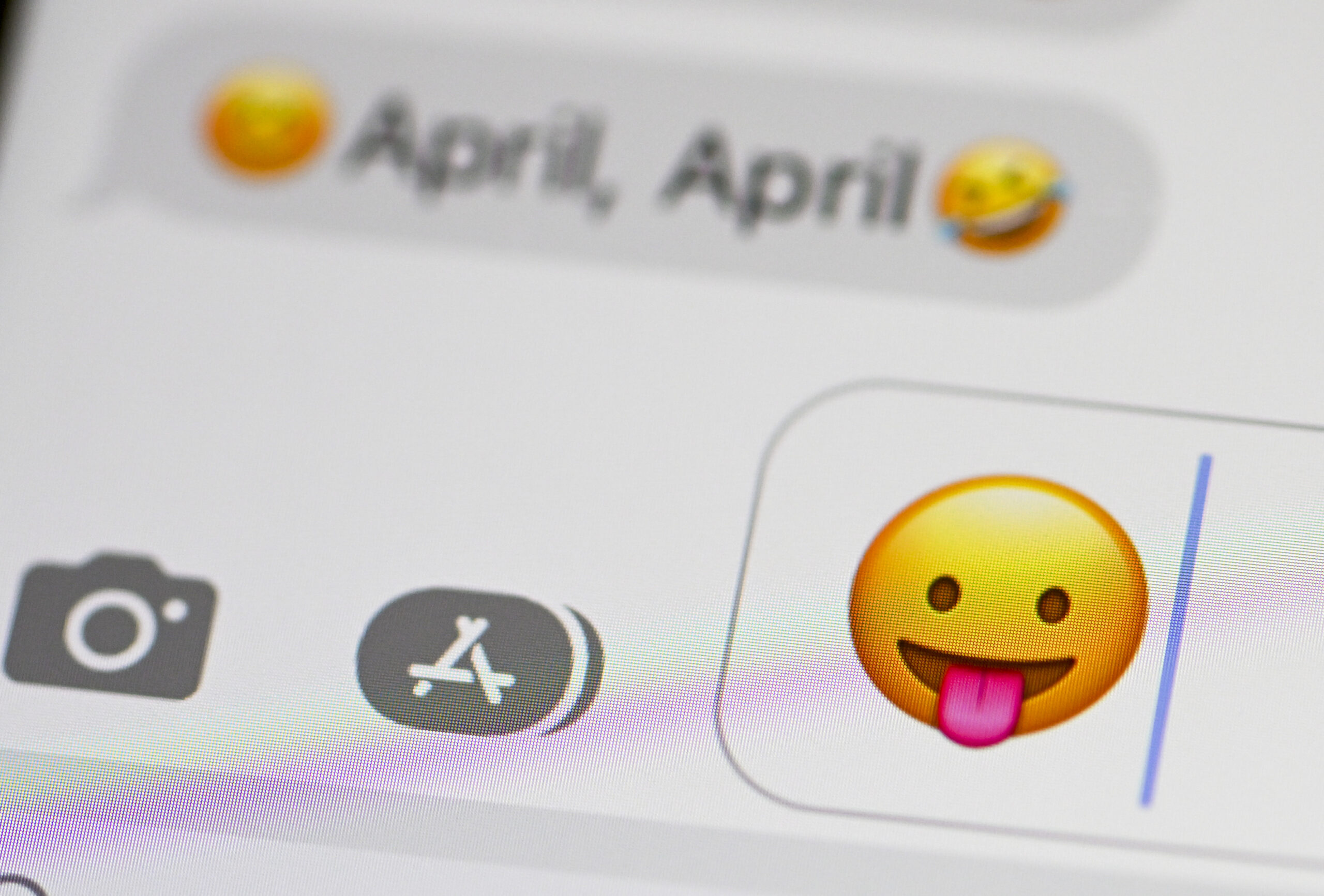 Auf einem Smartphone sind als Message „April, April“ und ein Smiley zu sehen, der die Zunge herausstreckt.
