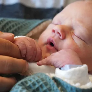 Schlafendes Baby hält Finger umklammert