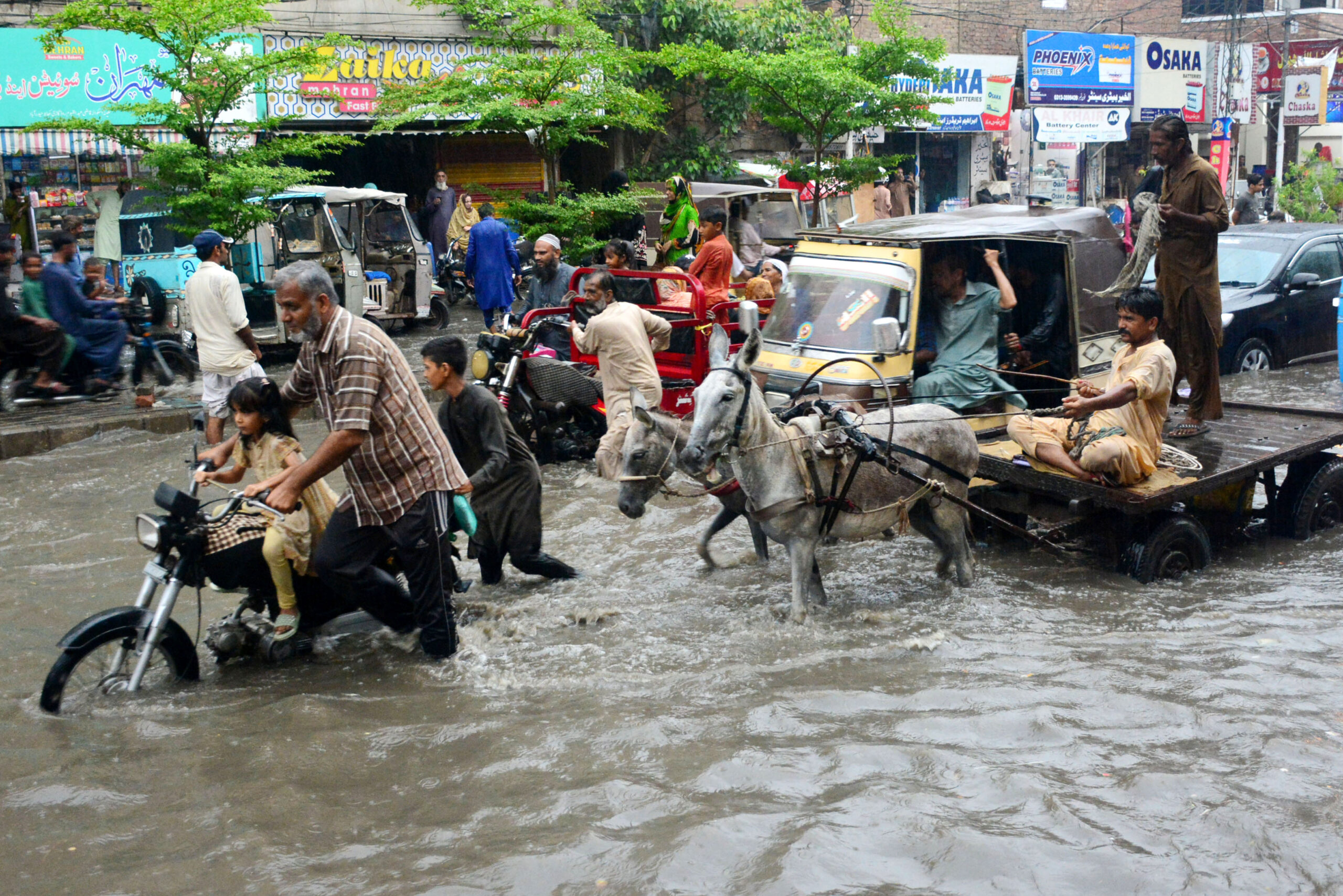 Menschen waten durch eine überflutete Straße nach starkem Monsunregen.