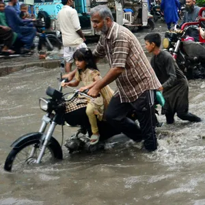 Menschen waten durch eine überflutete Straße nach starkem Monsunregen.