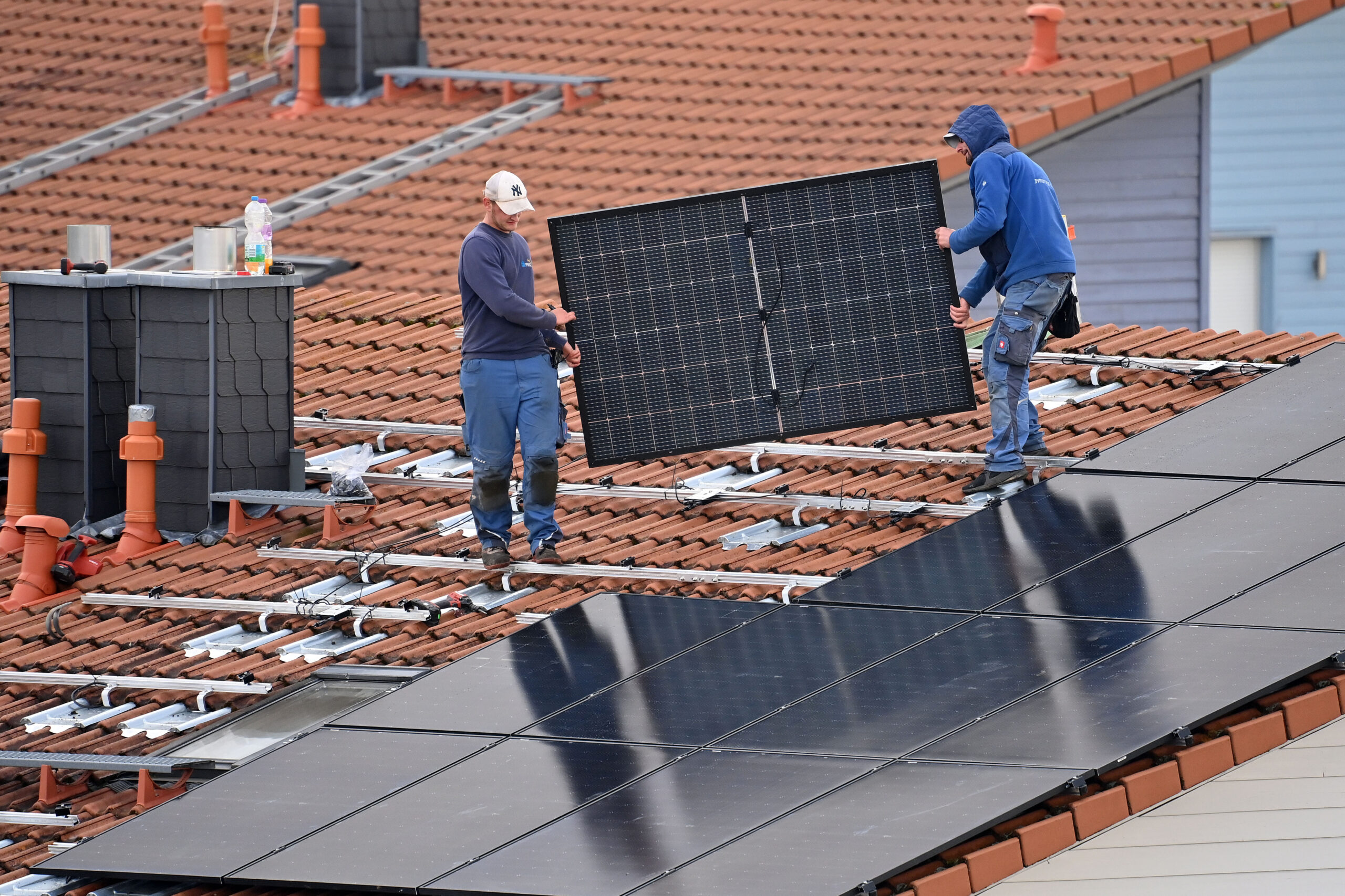 Arbeiter bei der Montage eines Solarpanels auf einem Hausdach