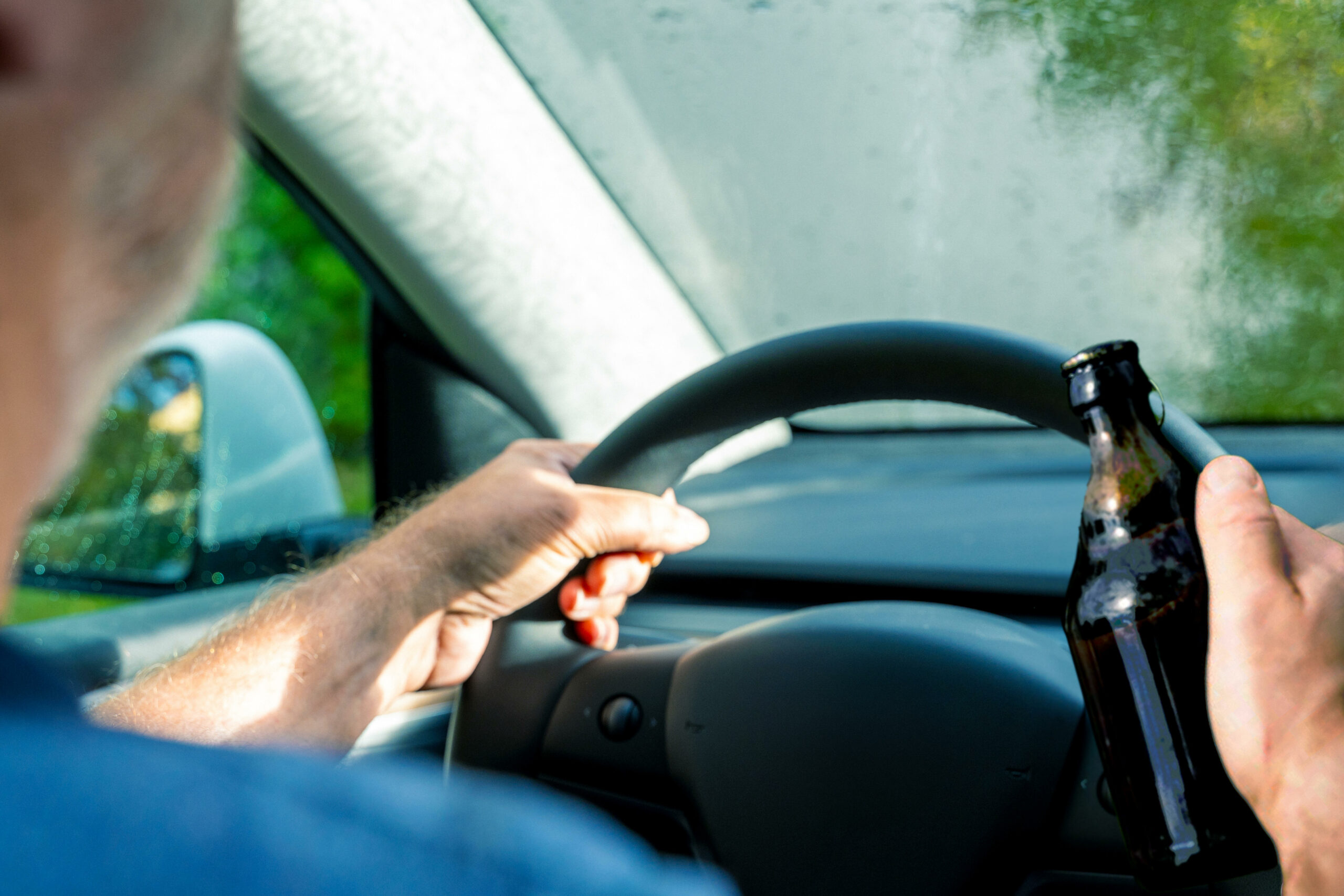 Person fährt Auto unter Konsum von Alkohol.