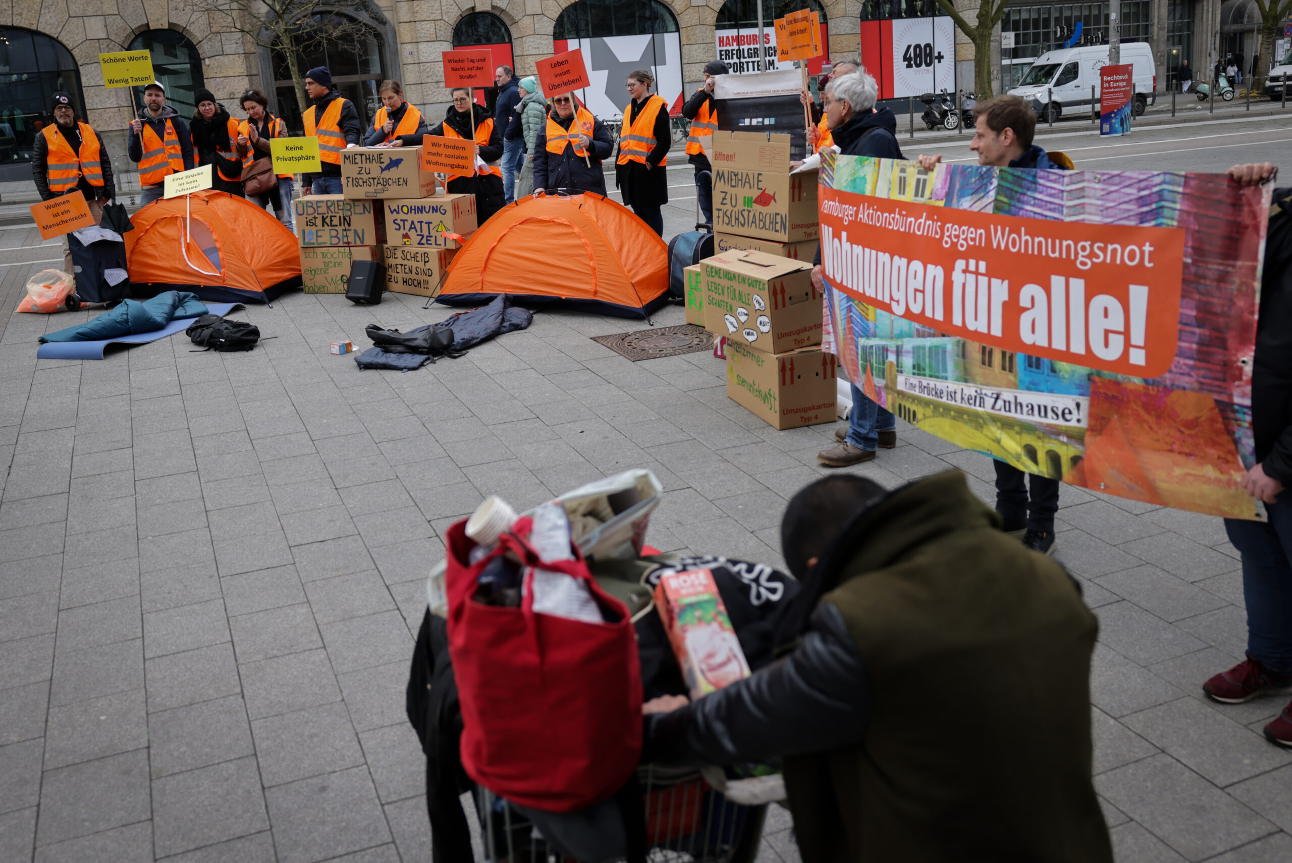 Aktivisten vor dem Hamburger Hauptbahnhof fordern auf einem Plakat „Wohnungen für alle“.