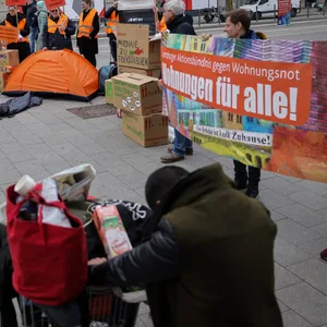 Aktivisten vor dem Hamburger Hauptbahnhof fordern auf einem Plakat „Wohnungen für alle“.