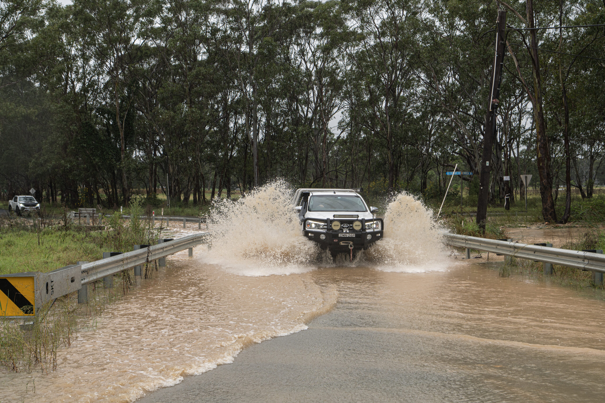 Ein Auto fährt über eine überschwemmte Straße in Vineyard, Sydney.