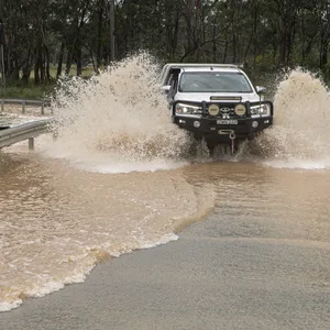 Ein Auto fährt über eine überschwemmte Straße in Vineyard, Sydney.