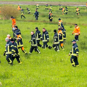 Einsatzkräfte laufen über ein Feld