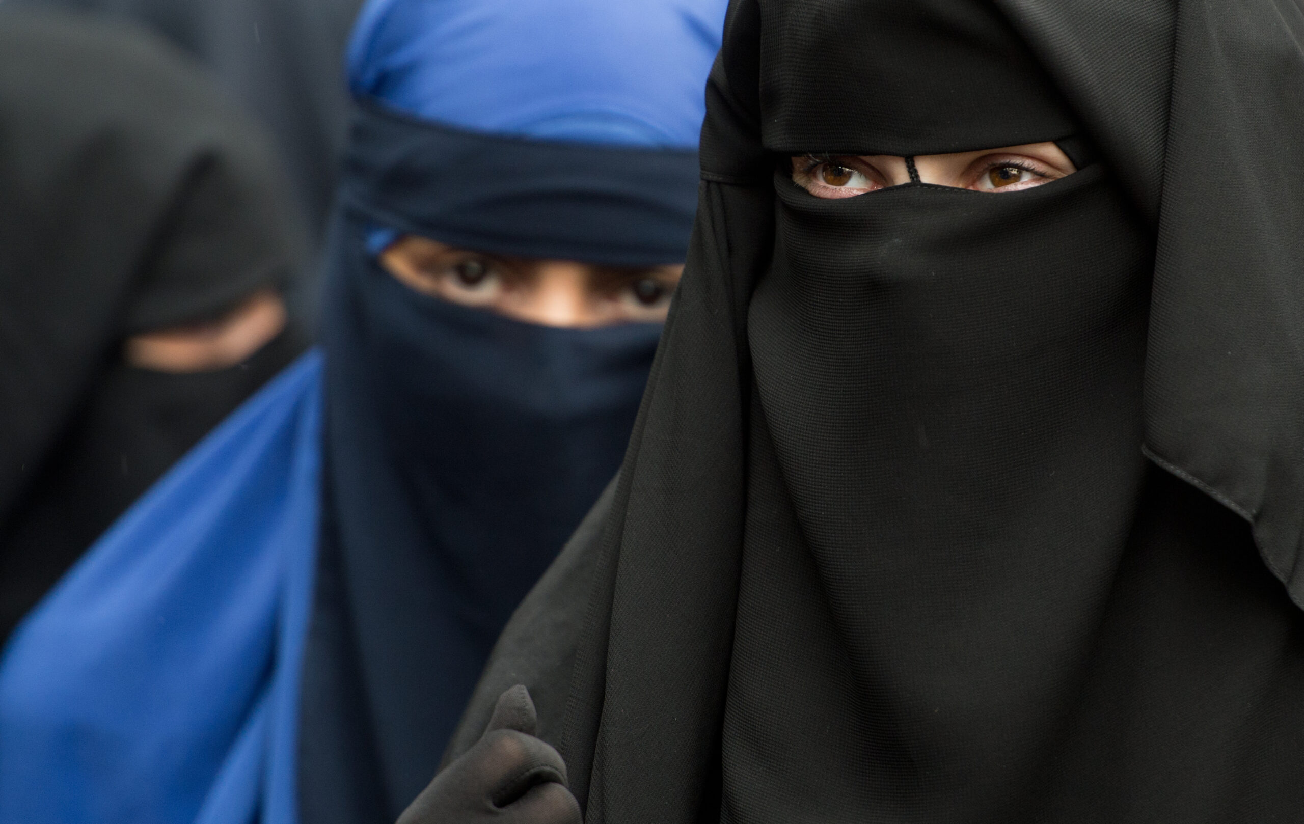 Eine vollverschleierte Frau schaut durch die Schlitze ihres Niqab