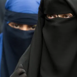 Eine vollverschleierte Frau schaut durch die Schlitze ihres Niqab