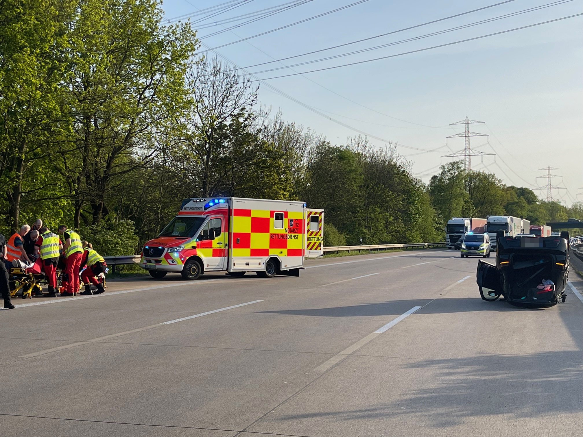 Rettungskräfte versorgen den verletzten Fahrer. Bei dem Unfall überschlug sich das Fahrzeug und kam auf dem Dach liegend zum Stehen.