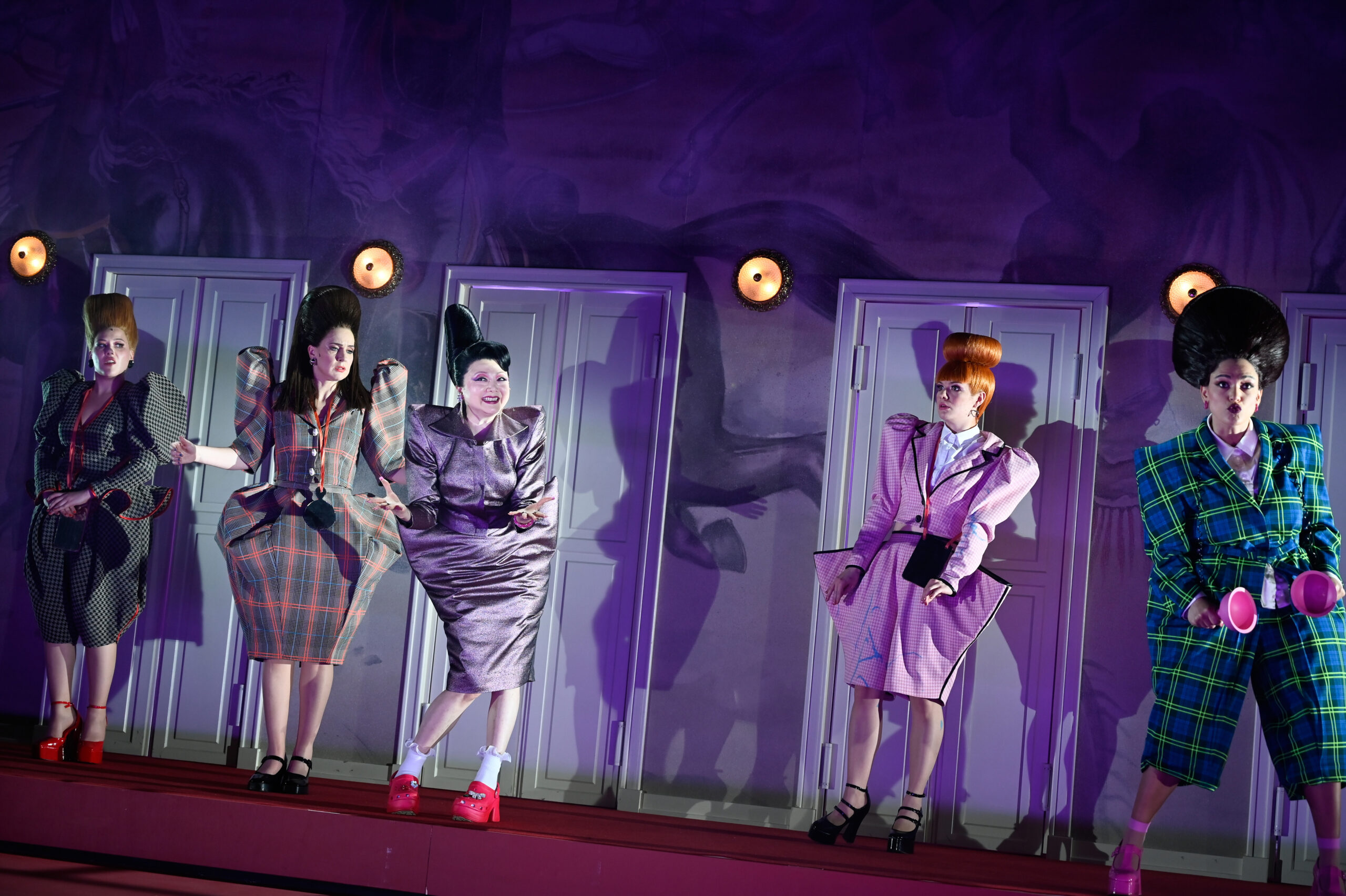 Fünf Frauen in schrägen Kostümen und Frisuren auf der dunklen Bühne