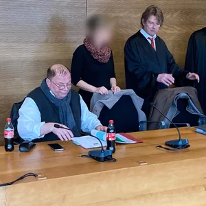 Die drei Angeklagten im Prozess wegen mutmaßlicher Beleidigung von Drosten mit ihren Anwälten.