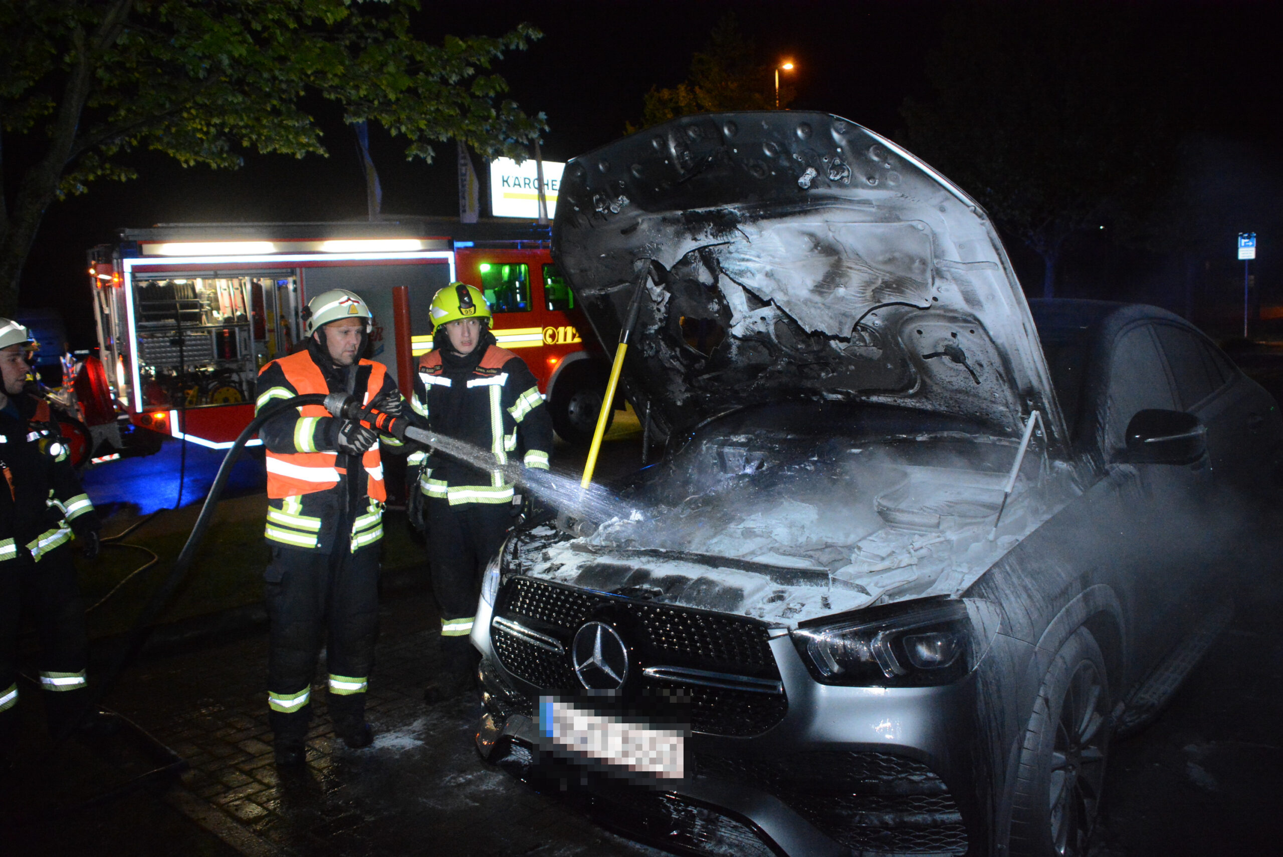 Einsatzkräfte löschen den brennenden Mercedes.