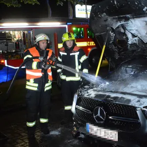 Einsatzkräfte löschen den brennenden Mercedes.