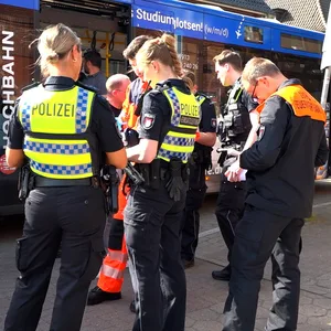 Einsatzkräfte von Polizei und Feuerwehr stehen vor dem Bus der Hochbahn..