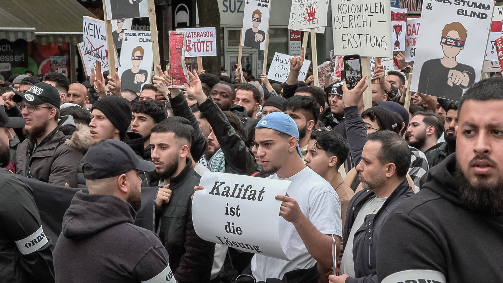 Männer auf Demo mit Schild: „Kalifat ist die Lösung“