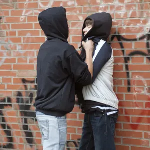 Ein Teenager drückt einen kleineren gewaltsam gegen eine Wand