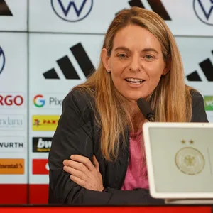 Nia Künzer lächelt auf einer Pressekonferenz.