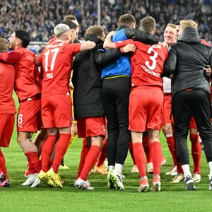 Die Heidenheim feiern auf dem Rasen.