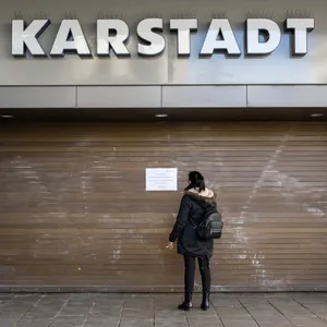 Eine Passantin steht vor einem geschlossenem Eingang der Karstadt-Filiale am Hauptbahnhof München.