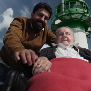 Ältere Dame und junger Mann vor Leuchtturm