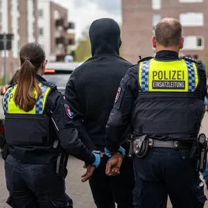Ein Mann wird in Handschellen abgeführt.