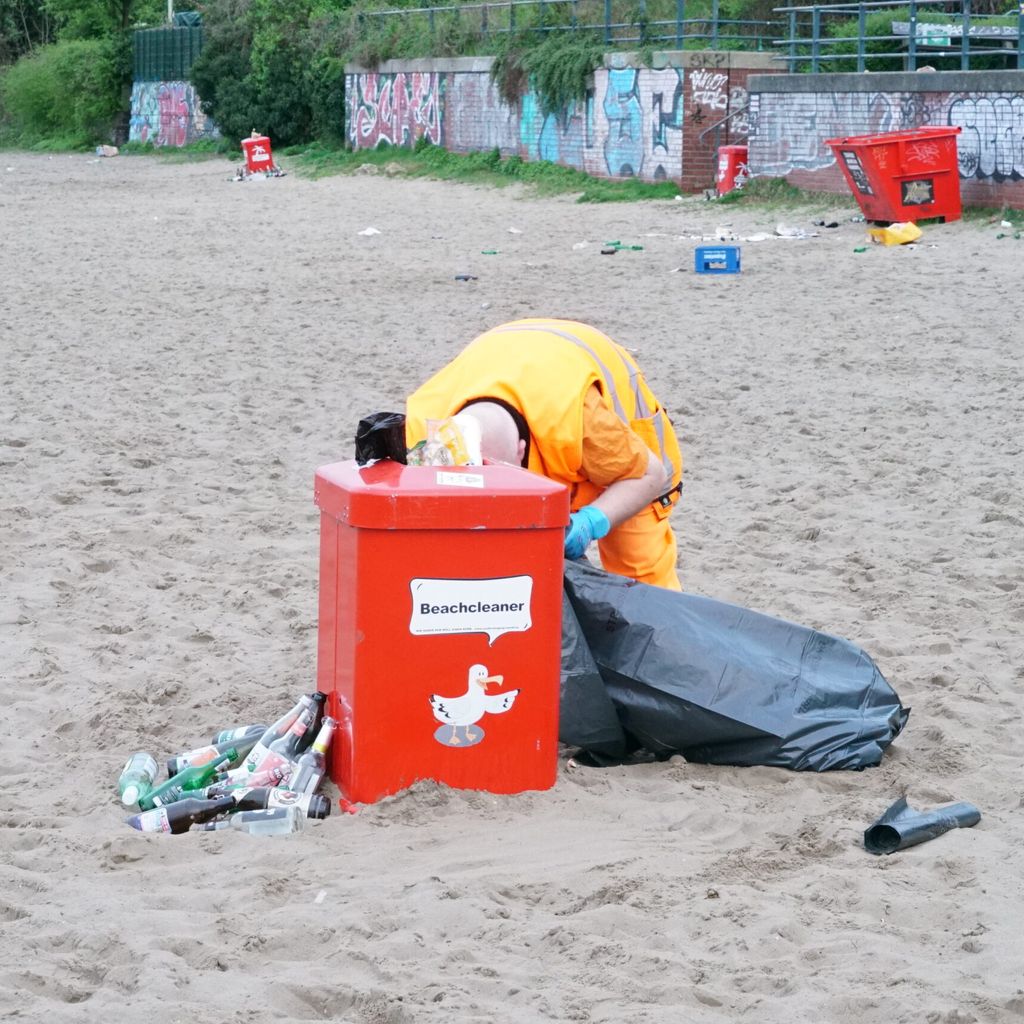 Ein Mitarbeiter der Stadtreinigung räumt am Elbstrand den Müll auf.