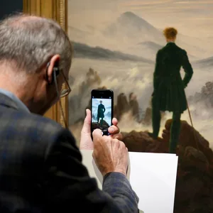 Ein Mann macht ein Handyfoto von einem Caspar-David-Friedrich-Gemälde