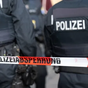 Polizisten stehen hinter einem Absperrband (Symbolbild).