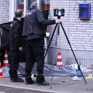 Zwei Männer sichern Spuren und Beweise neben der abgedeckten Leiche vor einer Kneipe in Düsseldorf.