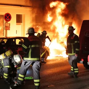 Feuerwehrkräfte löschen die Flammen vor dem Harburger Wohnhaus.