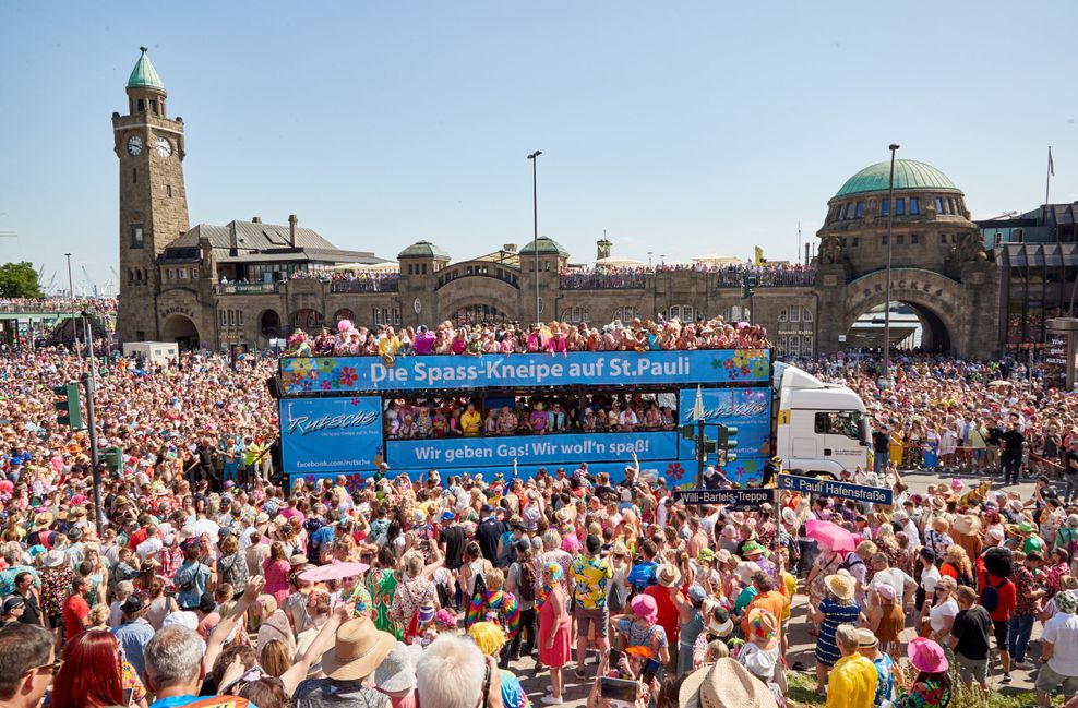 Zahlreiche Besucher fahren beim Schlagermove 2023 mit Wagen an den Landungsbrücken entlang und feiern zur Musik.