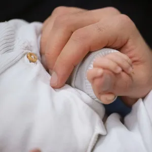 Baby hält die Hand eines Erwachsenen
