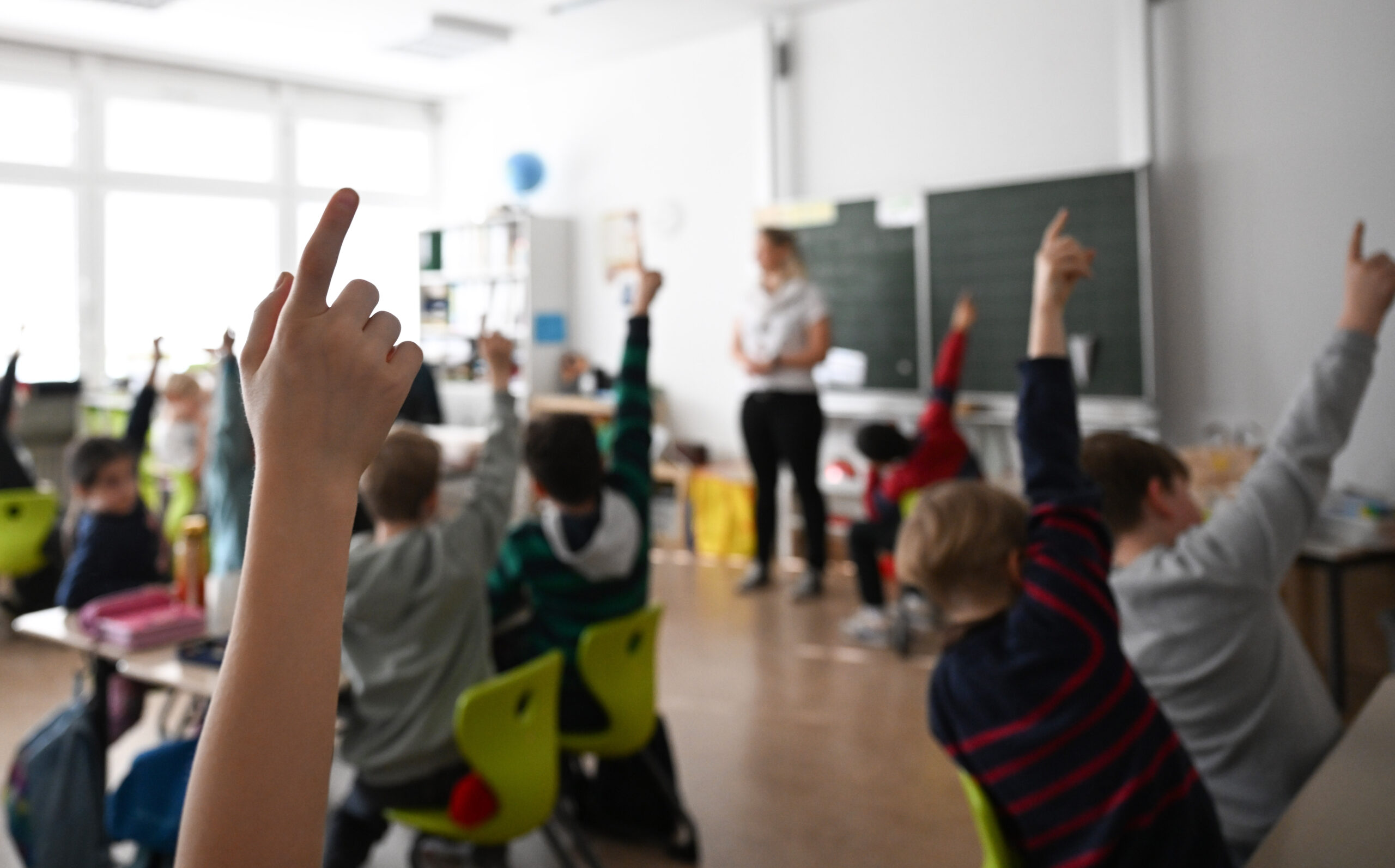 Kinder melden sich in einem Klassenzimmer