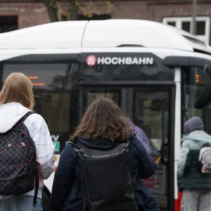 Mehrere Menschen stehen vor einem HVV-Bus (Symbolbild).