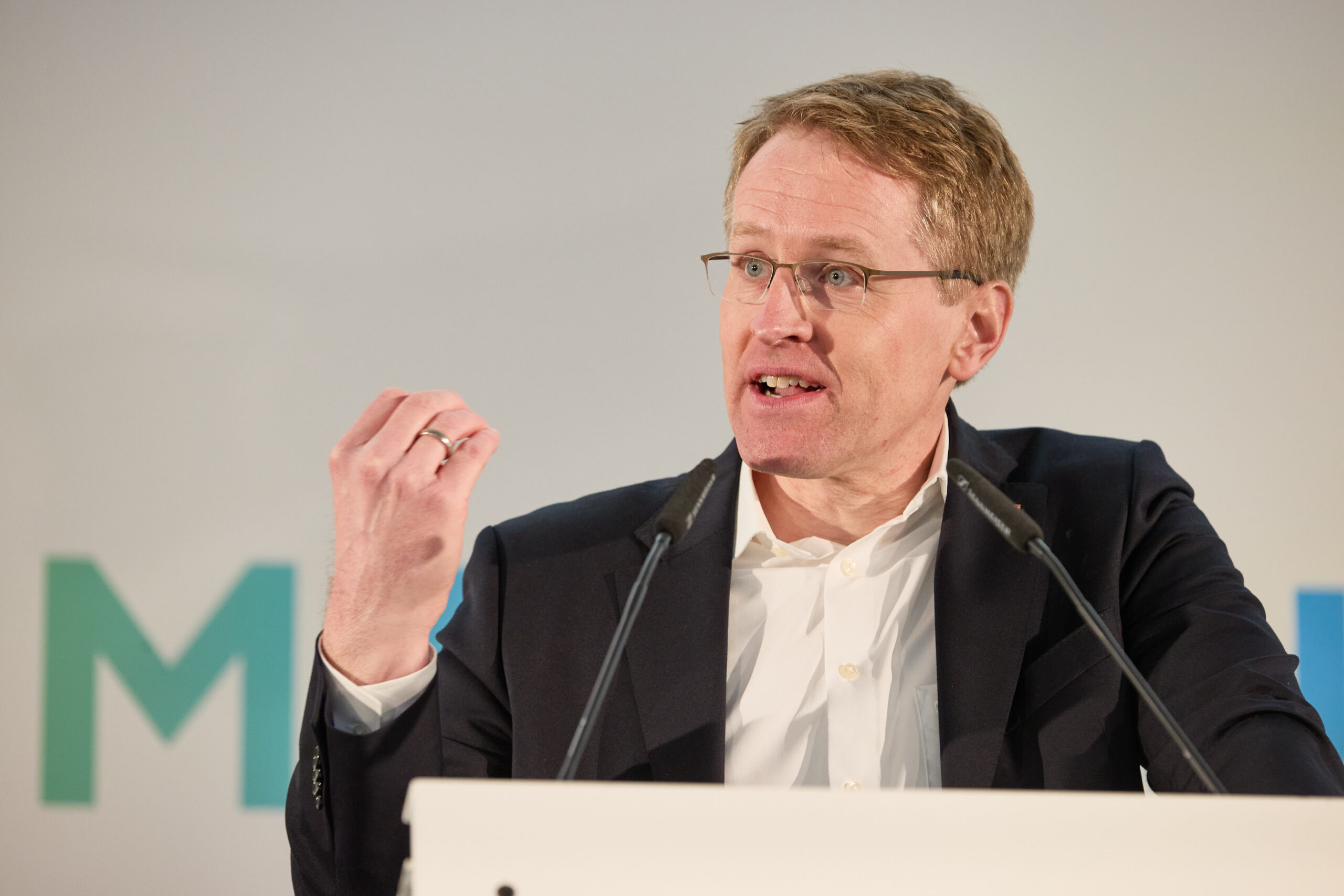 Blonder Mann mit Brille an Rednerpult