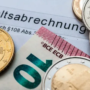 Geld – Münzen und ein 10-Euro-Schein – liegt auf einer Gehaltsabrechnung (Symbolbild).