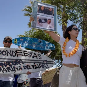 Eine Frau hält während einer Demonstration Fotos der verschwundenen ausländischen Surfer.