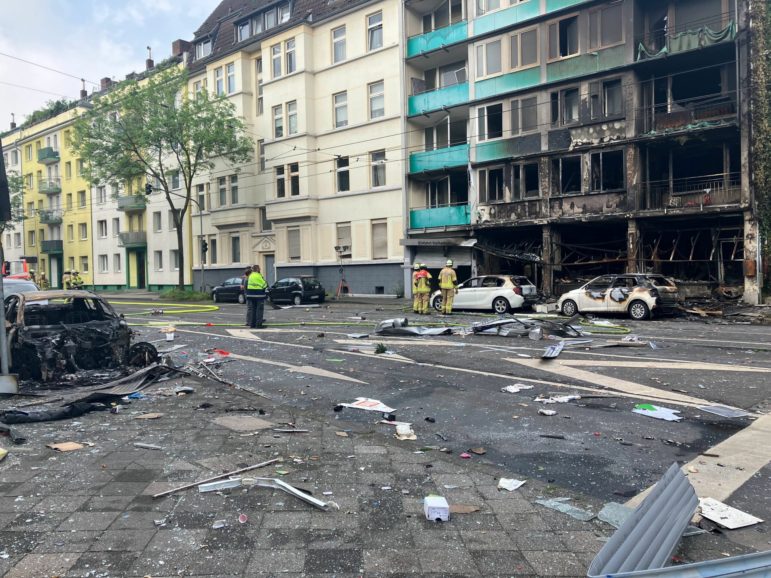 Auf der ganzen Straße liegen Trümmer, selbst gegenüber des Hauses ist ein Auto ausgebrannt: Mindestens drei Menschen starben bei dem verheerenden Feuer in Düsseldorf.