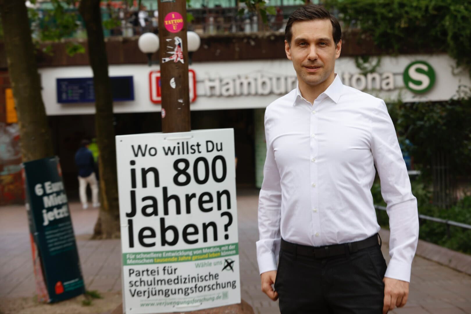 Mann an Plakat mit Aufschrift „Wo willst du in 800 Jahren leben?“