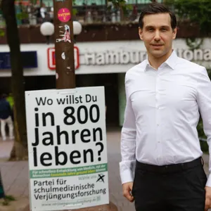 Mann an Plakat mit Aufschrift „Wo willst du in 800 Jahren leben?“