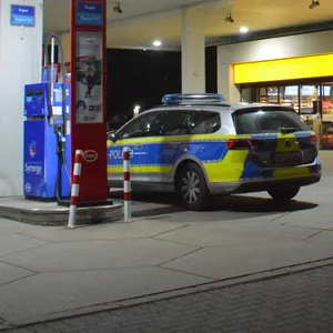 Eine Esso-Tankstelle, zwei Streifenwagen der Polizei stehen davor.