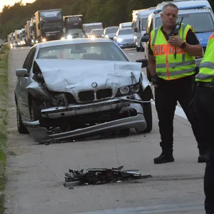Polizisten an zerbeultem silbernen BMW