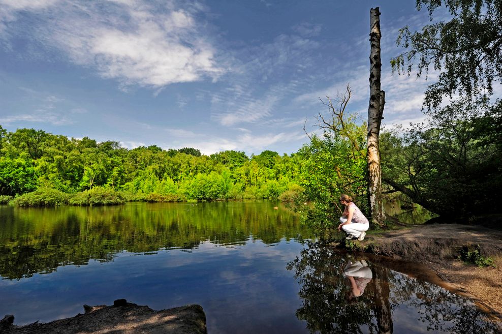 Frau kniet am Wasser