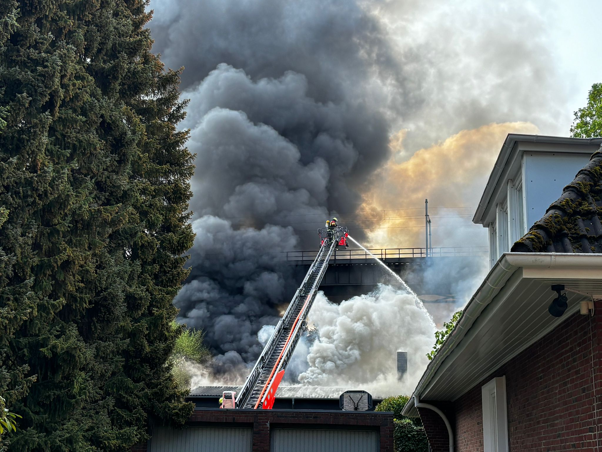 Ein Feuerwehrmann bekämpft die Flammen von einer Drehleiter aus.