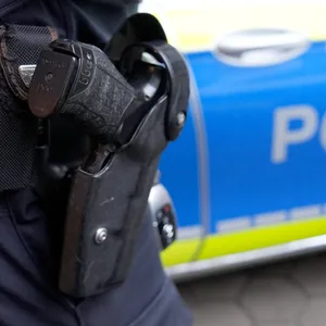Ein Polizist steht vor einem Einsatzfahrzeug der Polizei.