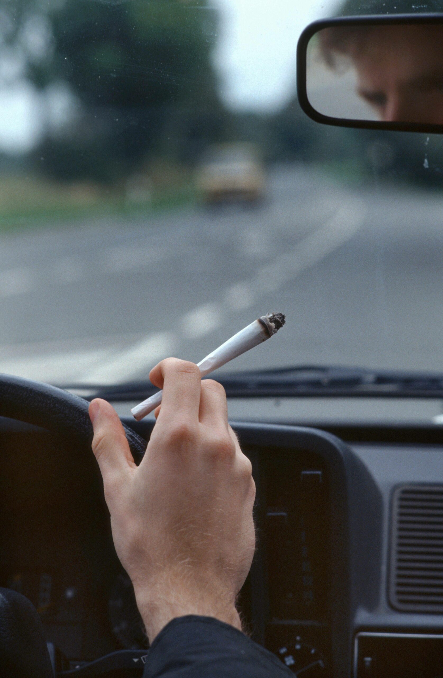 Ein Autofahrer raucht einen Joint während der Autofahrt.