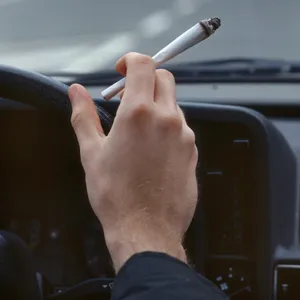 Ein Autofahrer raucht einen Joint während der Autofahrt.